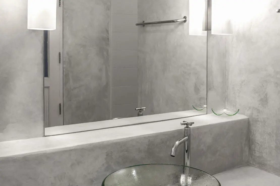 Salle de bain avec des murs et un comptoir en béton ciré gris.